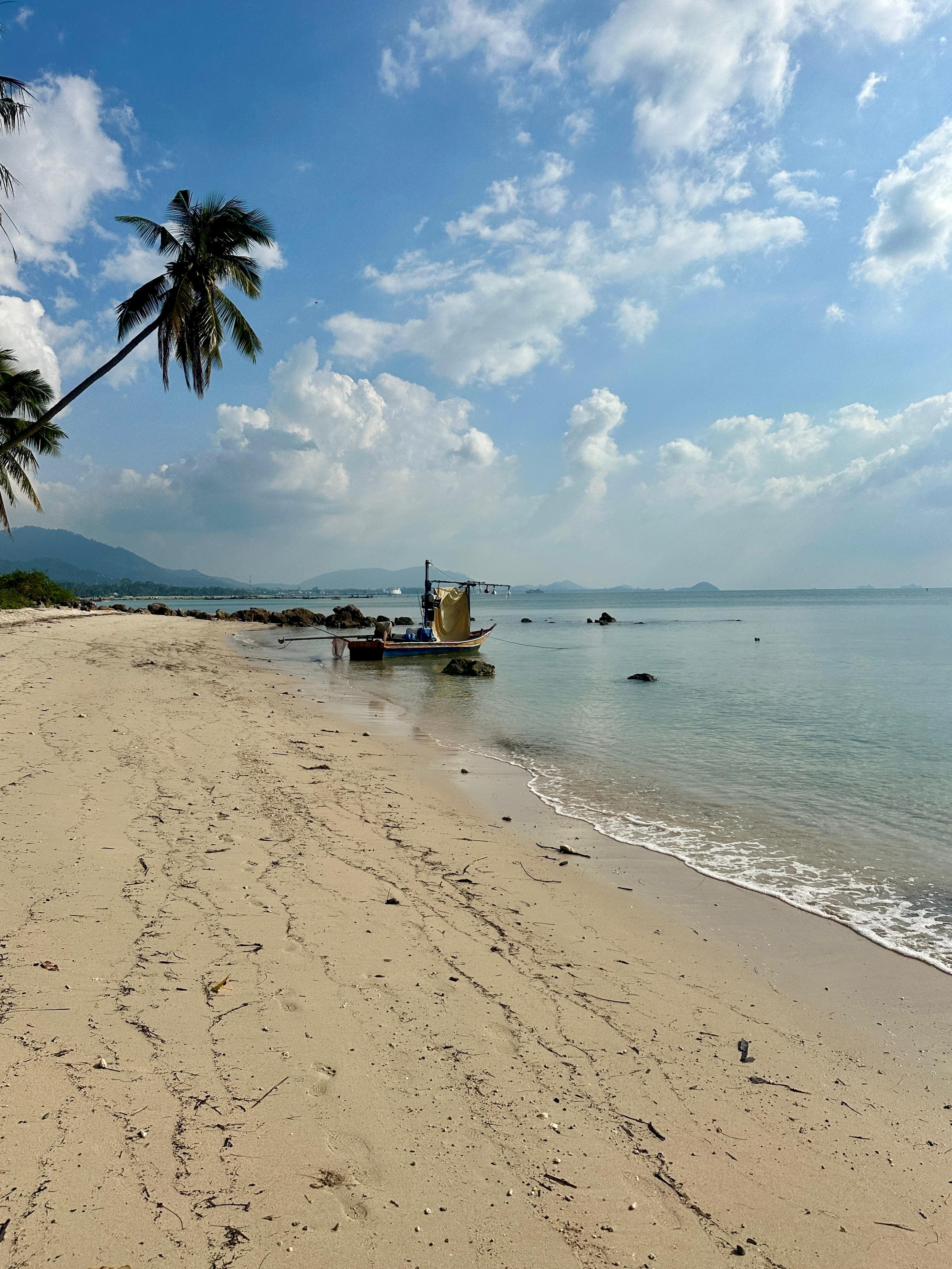 Łódź longtail przy brzegu spokojnej plaży na Koh Samui