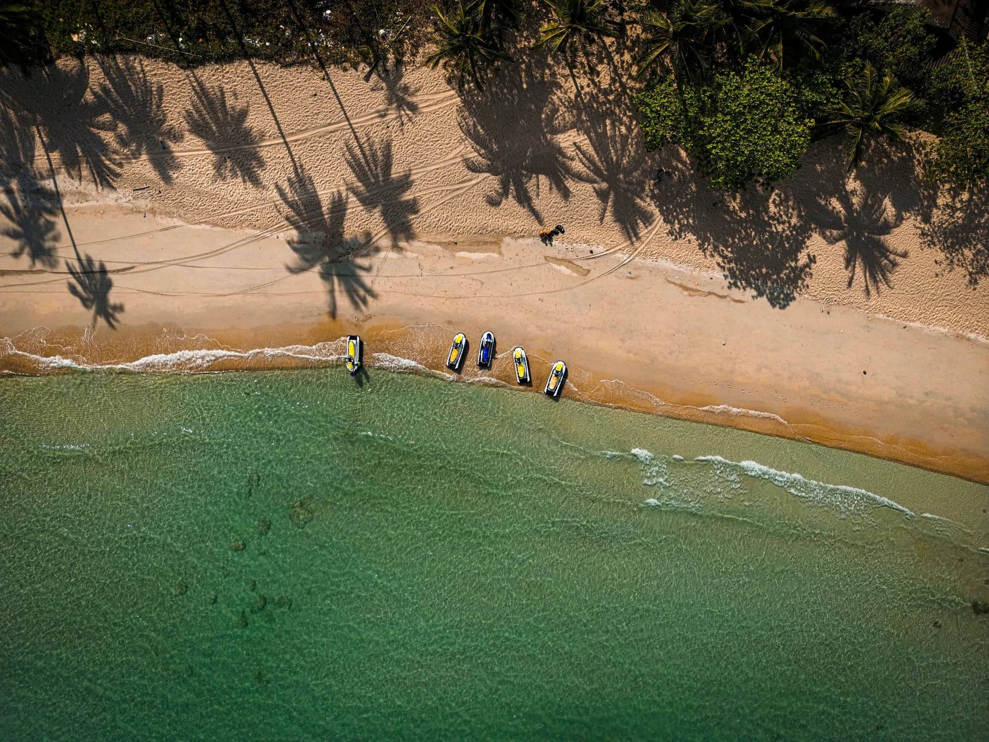 Ban Tai beach from above, with boats and palm shadows on the sand